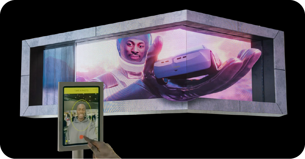 An example of interactive digital out-of-home (DOOH) advertising where a person uses a kiosk to take a photo that becomes part of a large 3D billboard ad featuring a futuristic scene.