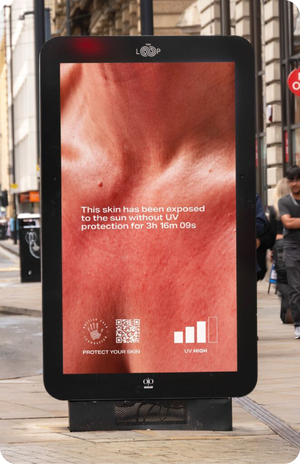 A smart digital out-of-home (DOOH) kiosk on a city street showing a real-time public health ad about UV exposure, displaying sunburnt skin and a QR code for a 'Protect Your Skin' campaign.