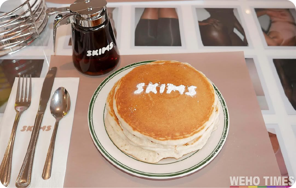 Stack of pancakes with the Skims logo in powdered sugar and branded syrup at the Skims Pop-Up Cafe, showcasing viral food marketing.